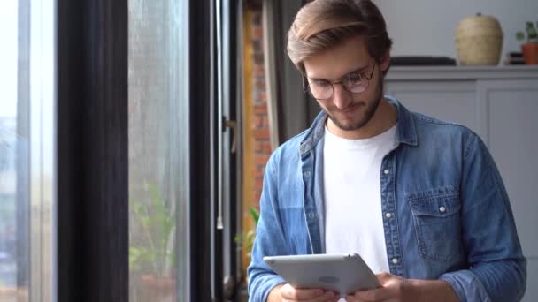 Joven trabajador profesional usando tableta digital de pie en la oficina en casa — Vídeos de Stock