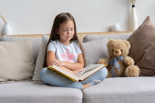 Een meisje dat thuis een boek leest. Afstandsonderwijs, thuisonderwijs. Zelfisolatieconcept. — Stockfoto