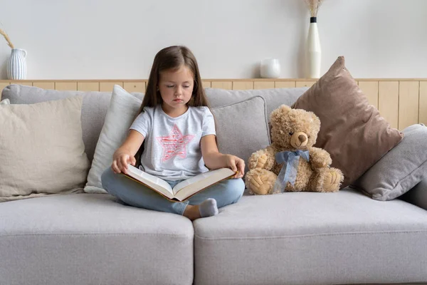 Ung flicka läser bok hemma. Distansutbildning, hemundervisning. Självisoleringskoncept. — Stockfoto