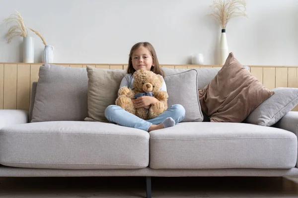 Positief lachend schoolmeisje liggend op een bank — Stockfoto