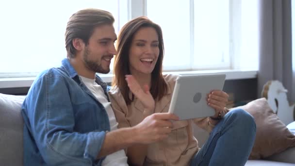 Glada par ringer ett videosamtal med en surfplatta hemma. — Stockvideo