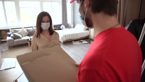 Deliveryman φορώντας μάσκα μεταφοράς κουτί παραδώσει στον πελάτη μπροστά από την πόρτα στο σπίτι — Αρχείο Βίντεο