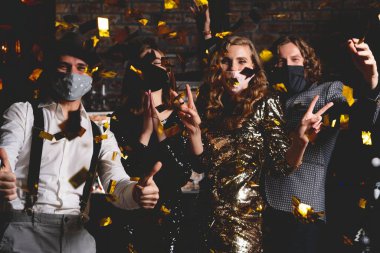 Corona virüsü salgını. Koruyucu maske takmış bir grup güzel genç insan dans ediyor, mutlu görünüyorlar.