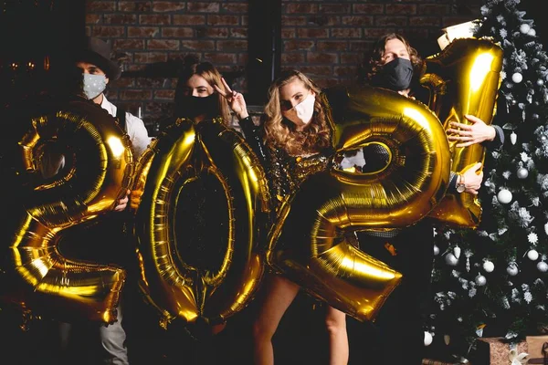 Концепція вечірки, людей та новорічних свят - жінок та чоловіків у захисній медичній масці, що святкують Новий рік 2021 року — стокове фото