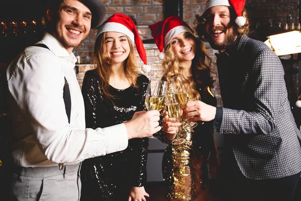 Njuter av nyårsfesten. Grupp av vackra ungdomar i Santa hattar dansar och ser glada ut. — Stockfoto