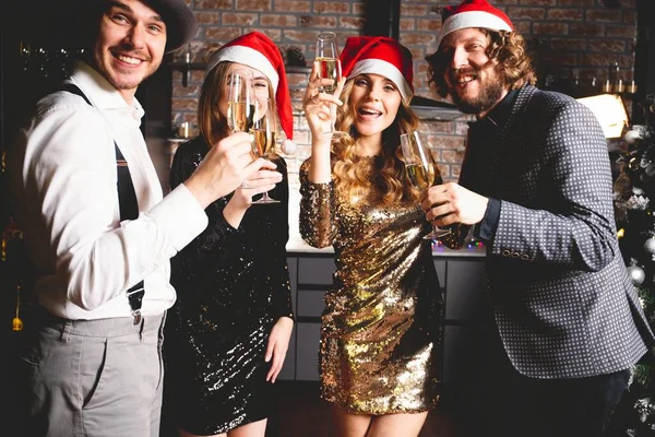 Njuter av nyårsfesten. Grupp av vackra ungdomar i Santa hattar dansar och ser glada ut. — Stockfoto