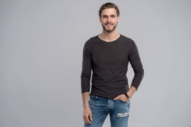 Gri arka planda duran zeki bir gencin portresi.