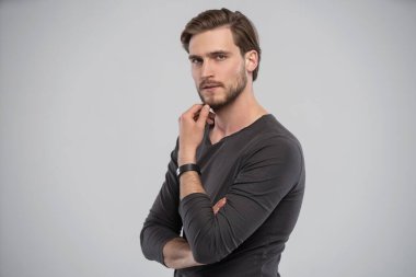 Gri arka planda duran zeki bir gencin portresi.