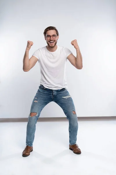 Feliz vencedor. Jovem feliz bonito homem gesticulando e mantendo a boca aberta enquanto está de pé contra o fundo branco. — Fotografia de Stock