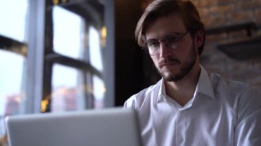 İşadamı odaklı girişimci dizüstü bilgisayarla araştırma yapıyor. Bilgisayarı kullanan genç profesyonel bir erkek ofis masasında oturuyor. Modern teknoloji not defteri üzerinde çalışan meşgul bir işçi..