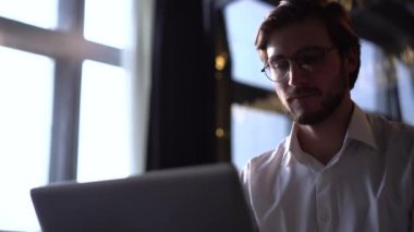 İşadamı odaklı girişimci dizüstü bilgisayarla araştırma yapıyor. Bilgisayarı kullanan genç profesyonel bir erkek ofis masasında oturuyor. Modern teknoloji not defteri üzerinde çalışan meşgul bir işçi..
