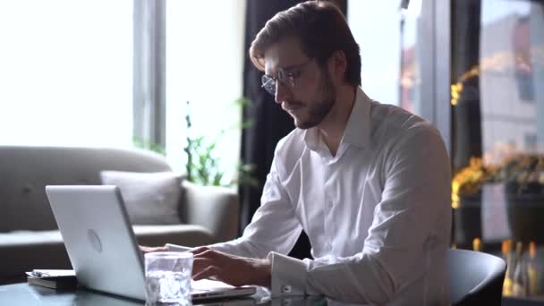 Entrepreneur homme d'affaires concentré tapant sur ordinateur portable faire de la recherche. Jeune professionnel masculin utilisant un ordinateur assis à la maison bureau. Travailleur indépendant occupé travaillant sur un appareil portable technologique moderne. — Video