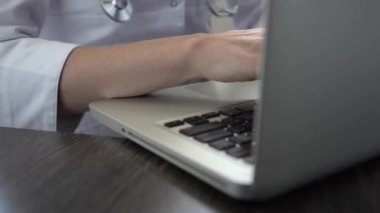 Bilgisayarda daktilo eden bir doktor, yakın plan. Doktor hastaların elektronik dosyalarını dolduruyor.