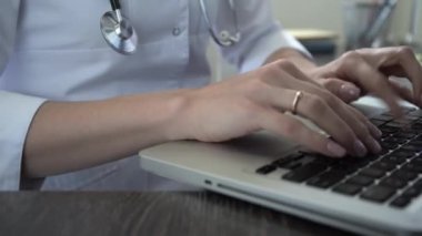 Bilgisayarda daktilo eden bir doktor, yakın plan. Doktor hastaların elektronik dosyalarını dolduruyor.