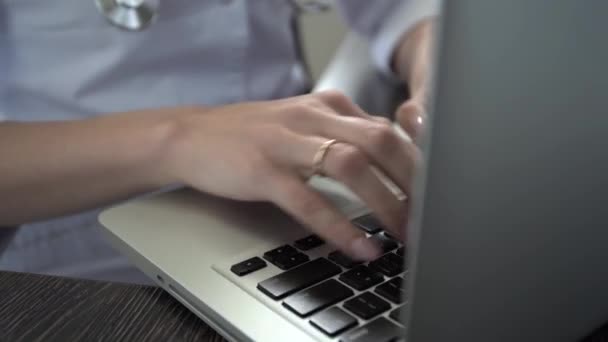 Doktorn skriver på laptop, närbild. Läkaren fyller i patientens elektroniska fil — Stockvideo