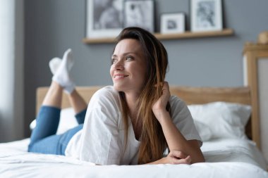 Yatakta uzanmış gülümseyen genç bir kadının portresi..