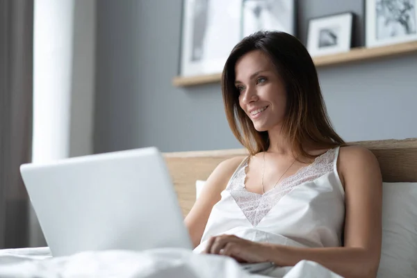 Pretty woman using her laptop in bed. — Stock Photo, Image