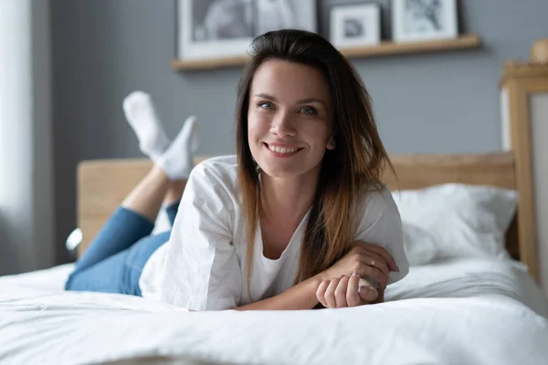 Retrato de uma jovem bonita e sorridente deitada na cama. — Fotografia de Stock