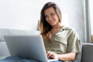 Oturma odasında dizüstü bilgisayar kullanan bir kadın. Karantina karantinasında evden çalışıyor. Sosyal uzaklık.