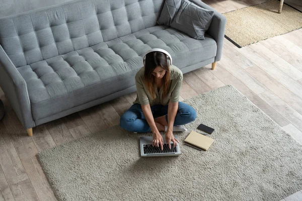 Solo inspirada. Joven confiada hermosa mujer sonriente que trabaja en el ordenador portátil mientras está sentado en el suelo en casa. — Foto de Stock