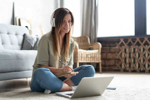 Juste inspiré. Confiant jeune belle femme souriante qui travaille sur ordinateur portable tout en étant assis sur le sol à la maison. — Photo