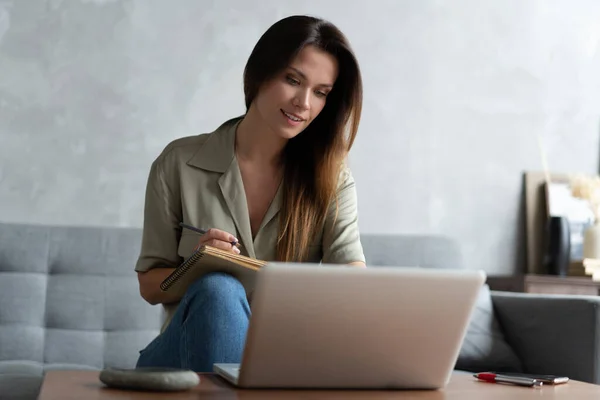 Wanita menggunakan laptop di ruang tamunya. Bekerja dari rumah di karantina kuncian. Jarak sosial. — Stok Foto