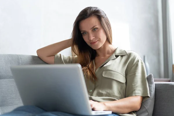 Wanita menggunakan laptop di ruang tamunya. Bekerja dari rumah di karantina kuncian. Jarak sosial. — Stok Foto