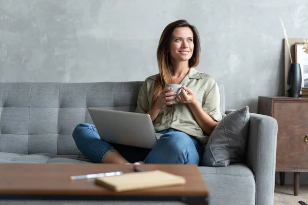 Mujer usando un portátil en su sala de estar. Trabajando desde casa en cuarentena. Distanciamiento social. — Foto de Stock