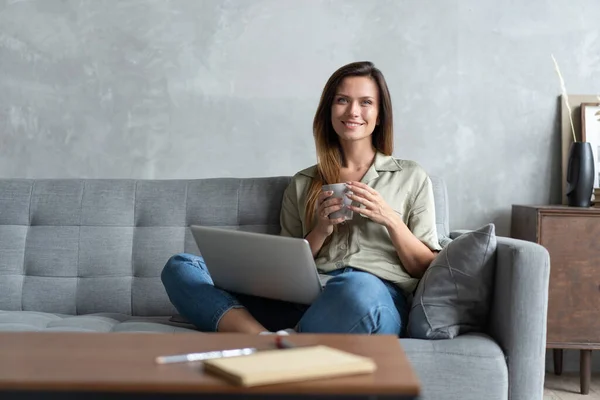 Mujer usando un portátil en su sala de estar. Trabajando desde casa en cuarentena. Distanciamiento social. — Foto de Stock