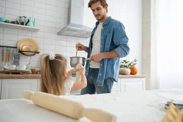 Cuidado joven caucásico padre y lindo poco preescolar hija hornear en cocina en casa juntos — Foto de Stock