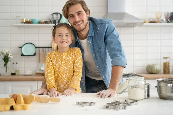 Alegre papá y su hija se divierten mientras amasan masa en la mesa de la cocina, hornear juntos — Foto de Stock
