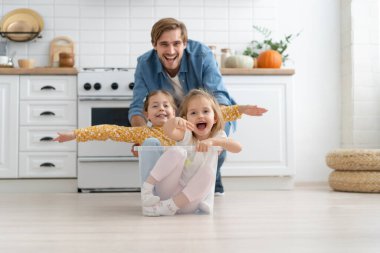 Heyecanlı, mutlu, genç bir baba koşuyor. Küçük şirin çocuklarla dolu karton kutuları itiyor. Kızları da içeri girip eğleniyor..