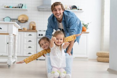 Heyecanlı, mutlu, genç bir baba koşuyor. Küçük şirin çocuklarla dolu karton kutuları itiyor. Kızları da içeri girip eğleniyor..
