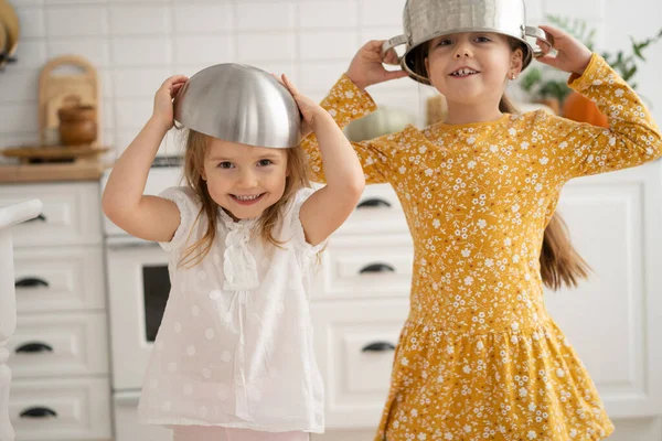 Lindos niños pequeños que usan un tazón como casco y juegan en casa. — Foto de Stock