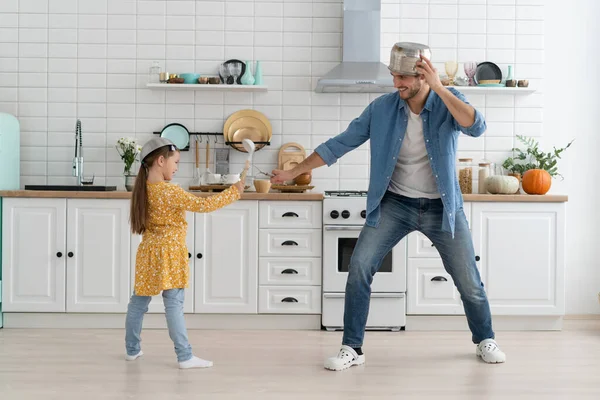 Caucasian father and daughter enjoy battle funny activity in kitchen spend active time together on weekend at home Stock Photo