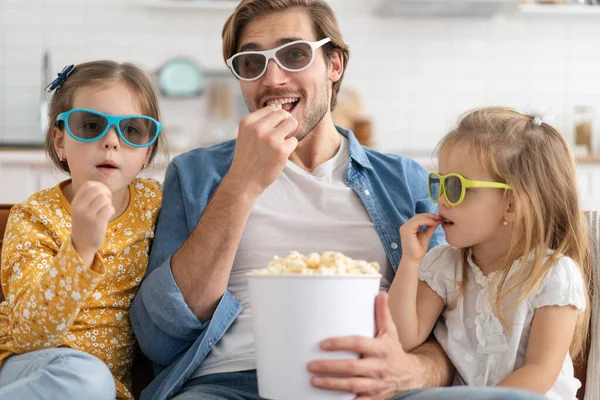 Šťastná rodina sleduje televizi doma a jí popcorn. — Stock fotografie