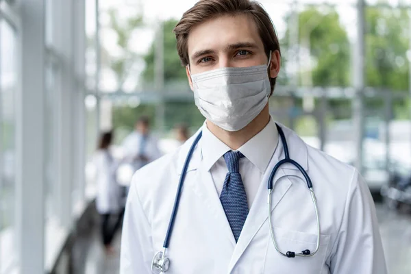 Mannelijke arts portret in het ziekenhuis met gezichtsmaskers op zoek naar camera, corona virus concept — Stockfoto