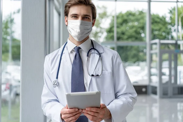 Mannelijke arts portret in het ziekenhuis met gezichtsmaskers op zoek naar camera, corona virus concept — Stockfoto