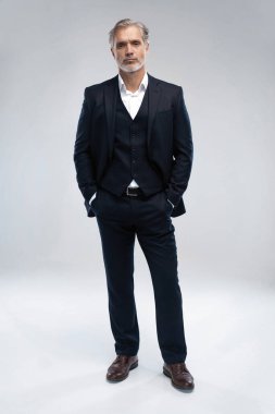 Yetişkin bir iş adamının takım elbise giyip kameraya baktığı uzun bir çekim.