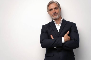 Gri arkaplana karşı poz veren orta yaşlı yakışıklı bir adam.