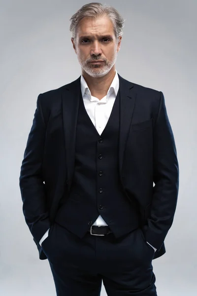 Handsome middle-aged man in suit posing against grey background