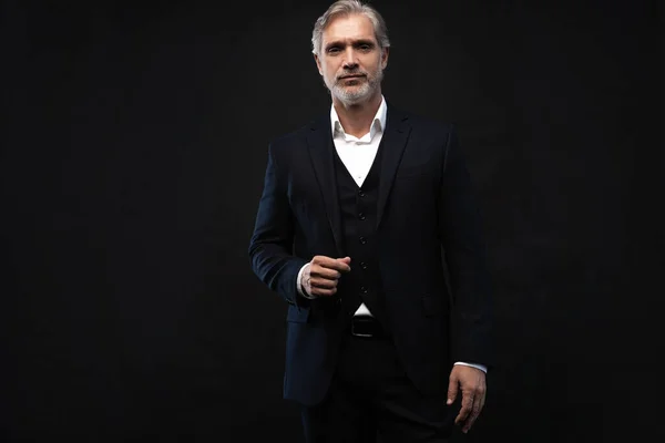 Handsome middle-aged man in suit posing against black background