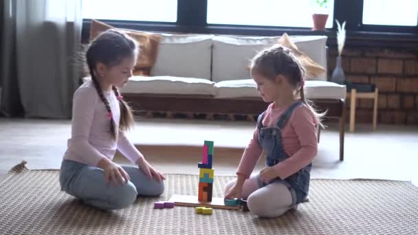 Happy Sisters duduk di karpet, bermain dengan kayu konstruktor berwarna-warni — Stok Video