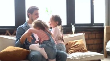 Mutlu aile kızları ve babaları kanepede birlikte yatarak eğleniyorlar.