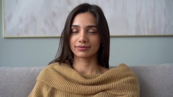 Attractive Indian mixed-race woman looking at camera sit on sofa alone at home — Stock Video
