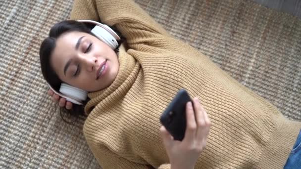 Mujer india de raza mixta en auriculares escuchando música favorita sosteniendo el teléfono — Vídeos de Stock