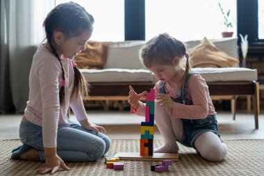 Çocuklar odalarında yerde yatan tahta bloklarla oynuyorlar..