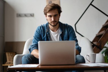 Bir dizüstü bilgisayarla çalışan ve küçük bir ofiste ya da evde bir belge tutan girişimci