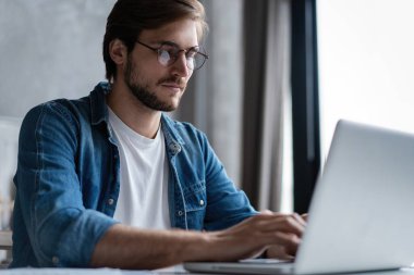 Başarılı girişimci çalışırken bilgisayarındaki bilgileri kontrol ederken tatmin olmuş bir şekilde gülümsüyor.