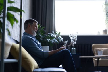 Olgun yakışıklı adam evde tablette web sörfü yapıyor..